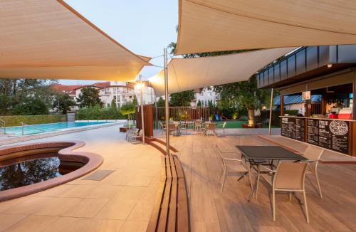 um pátio com uma mesa e cadeiras e uma piscina em Hotel Barátság em Hajdúszoboszló