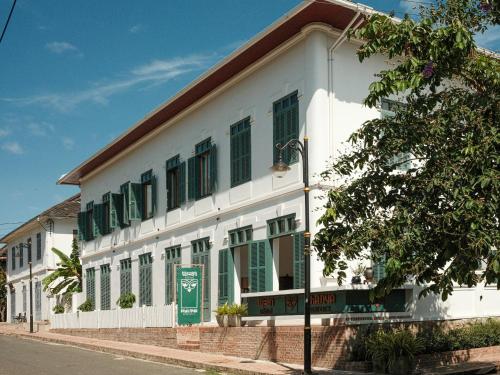 un edificio blanco con persianas verdes en una calle en PHA NYA RESIDENCE, en Luang Prabang