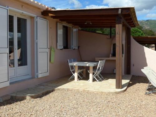 um pátio com uma mesa e cadeiras em frente a uma casa em Domaine San Sebastiano em Porto-Vecchio