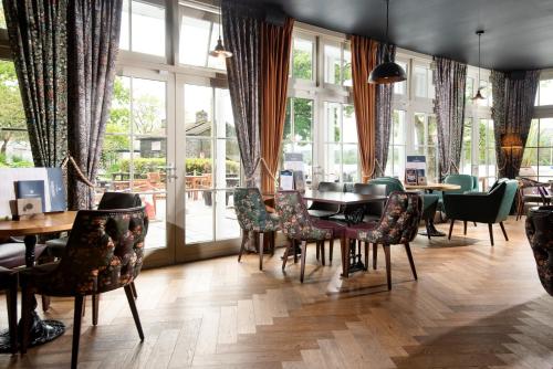 een eetkamer met tafels, stoelen en ramen bij The Waterhead Inn- The Inn Collection Group in Ambleside