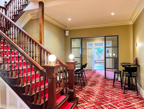 una escalera en una habitación con sillas y mesa en Tempe Hotel Sydney, en Sídney