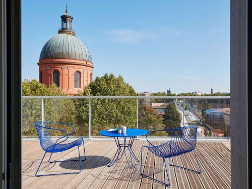 un tavolo e sedie su un balcone con un edificio di Aparthotel Adagio Original Toulouse Centre La Grave a Tolosa