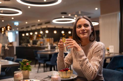 a woman sitting at a table drinking a glass at Boutique Hotel Germania in Munich