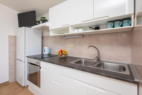 a kitchen with white cabinets and a sink at La Playa Beach Apartment in Omiš