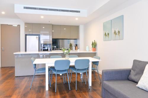 cocina y sala de estar con mesa blanca y sillas en Sydney CBD Modern 2 bedroom Apartment, en Sídney