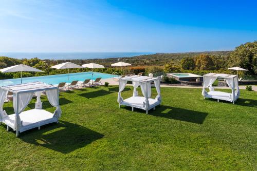 un grupo de sillas y sombrillas blancas junto a una piscina en Kepos Etna Relais & Exclusive Spa, en Santa Venerina