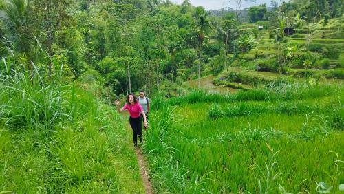 a woman walking on a dirt path in a field at Hide and Seek in Tetebatu