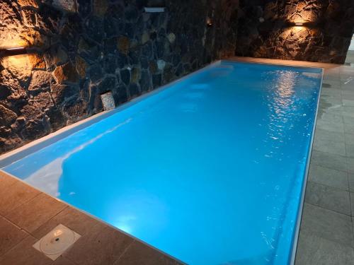 a pool with blue lighting in a room with a stone wall at Luxury Apartment 150 m from the beach in Flic-en-Flac