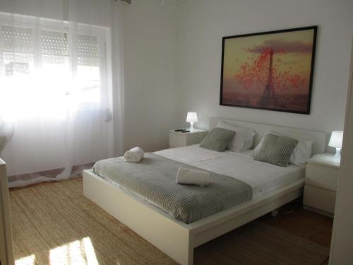 um quarto branco com uma cama branca e uma janela em Centro Cidade Holiday em Portimão