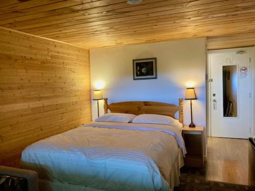 een slaapkamer met een groot bed en houten wanden bij Castle Rock Country Inn in Ingonish Beach