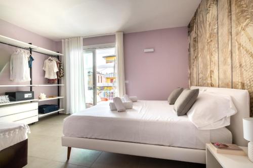 a bedroom with a large white bed with purple walls at Residence Lido di Dante in Lido di Jesolo