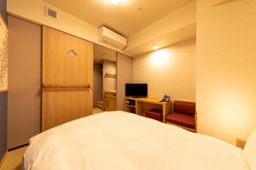 a room with a bed and a desk and a television at Onyado Nono Asakusa Natural Hot Spring in Tokyo