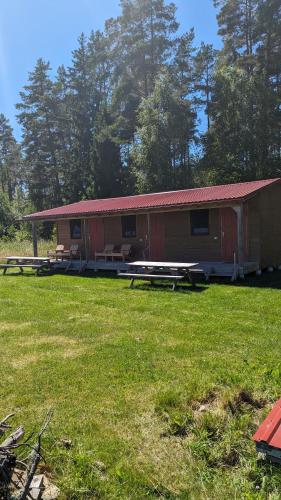 una cabaña con mesas de picnic en un campo de hierba en Strautmali Forest House, en Mazirbe