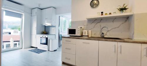 cocina blanca con fregadero y microondas en Apartman Family, en Crikvenica