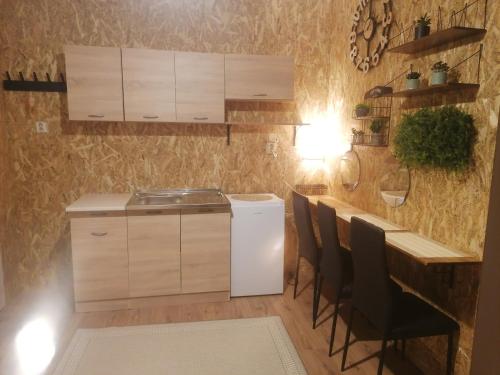 a kitchen with a sink and a counter with chairs at Apartman ClaRa in Štúrovo