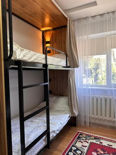 a bunk bed room with two bunk beds and a window at Hostel Saruu in Bishkek