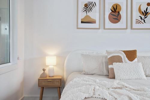 a bedroom with a bed with a white bedspread and pictures on the wall at Harbour Marina - Absolute waterfront apartment in Batemans Bay