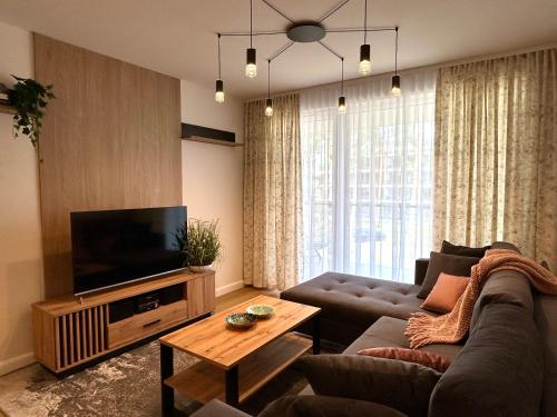 een woonkamer met een bank en een flatscreen-tv bij Apartament Augustów in Augustów