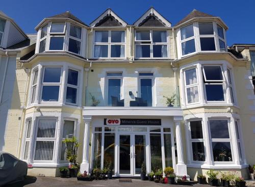 uma grande casa branca com um edifício cdo em OYO Minerva Guesthouse em Newquay