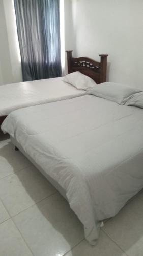 2 letti con coperte e cuscini bianchi in una camera da letto di HOSTAL CARACOLI - HUECO a Valledupar