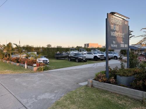 ein Schild für ein Hotel mit Autos auf einem Parkplatz in der Unterkunft Lakeside Motel Waterfront in Lakes Entrance