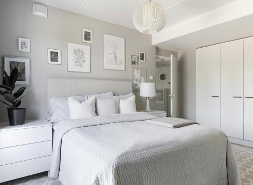 Dormitorio blanco con cama blanca y maceta en Upea 117,5m2 huoneisto Helsingin keskustassa, en Helsinki