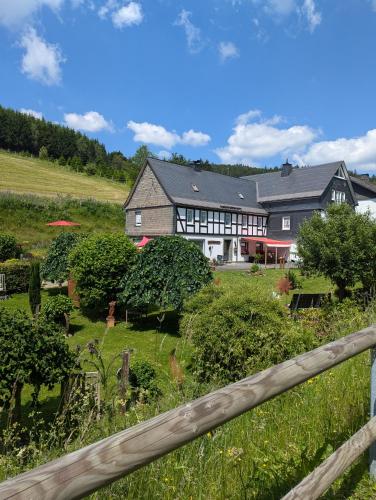 ein großes Haus auf einem Feld mit einem Zaun in der Unterkunft Ferienwohnung Soreth in Schmallenberg