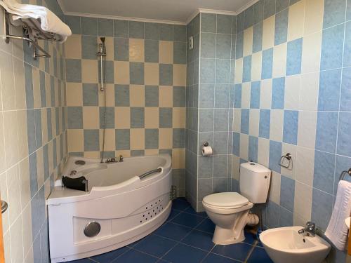 a bathroom with a tub and a toilet and a sink at Guest House Golden Flake 4km from Bolata beach in Bŭlgarevo