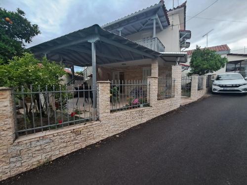 una cerca frente a una casa con un coche en Traditional Stone House-Ideal for families, en Archea Pissa