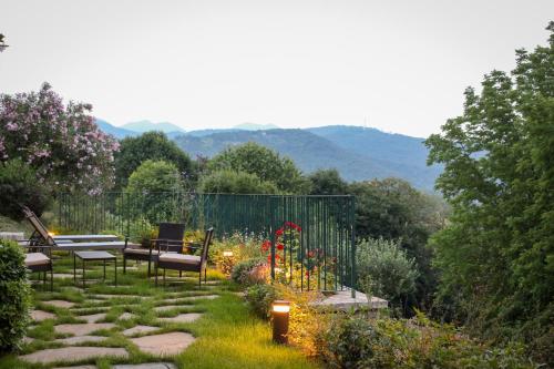 einen Garten mit Bänken und Blumen mit Bergen im Hintergrund in der Unterkunft La Valletta Relais in Bergamo