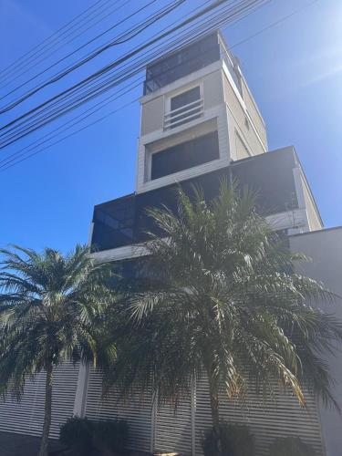 un edificio alto con palmeras delante en Talli Hotel, en Curitiba