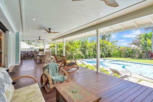 eine Innenterrasse mit einem Tisch, Stühlen und einem Pool in der Unterkunft Gorgeous Renovated 1937 Plantation Style Beach House 50 Steps to the Center of the Beach home in Kailua