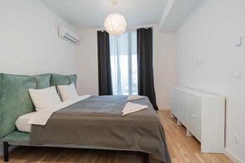 - une chambre avec un lit et un lustre dans l'établissement Lagoon Park Apartments with Beach View, à Bucarest