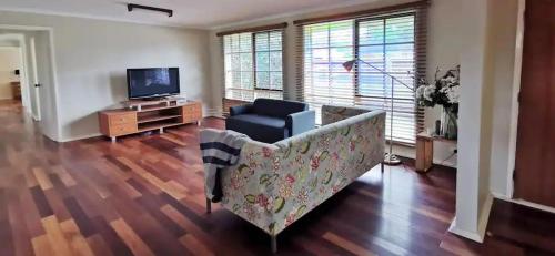 Spacious and cozy home next to Glen Waverley في Wantirna South: غرفة معيشة مع أريكة وتلفزيون