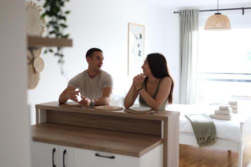 een man en vrouw aan een tafel in een kamer bij Studio Apartman Boho in Sombor