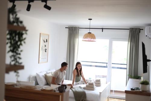 een man en vrouw zittend op een bed in een woonkamer bij Studio Apartman Boho in Sombor