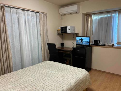 Cette chambre comprend un lit et un bureau avec un ordinateur. dans l'établissement Guest House Harukawa, à Osaka