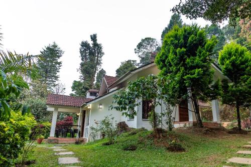 une maison blanche avec un arbre dans la cour dans l'établissement Three Hills Resort Coorg, à Madikeri