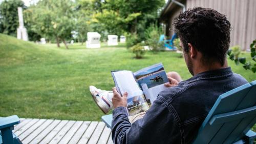 Un uomo seduto su una sedia a leggere un libro di Hotel Landhafen a Niebüll