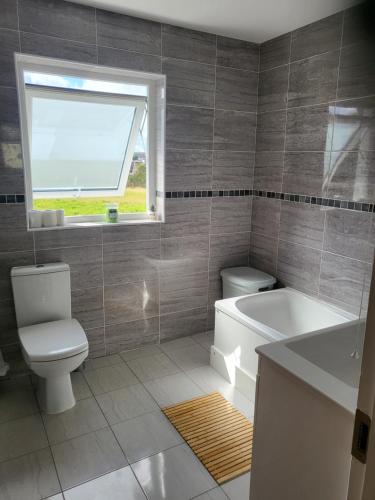 ein Bad mit einem WC, einer Badewanne und einem Fenster in der Unterkunft Fortlands in Kiltimagh