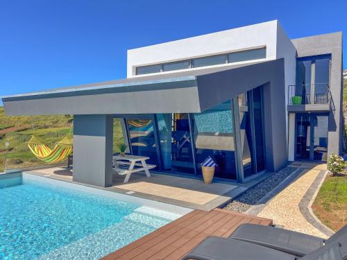 een villa met een zwembad en een huis bij Villa Leonor Cliffside Retreat in Calheta