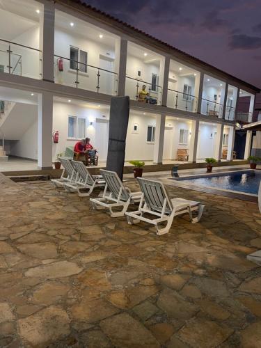 une rangée de chaises de jardin devant un bâtiment dans l'établissement Hotel Kenito, à São Tomé