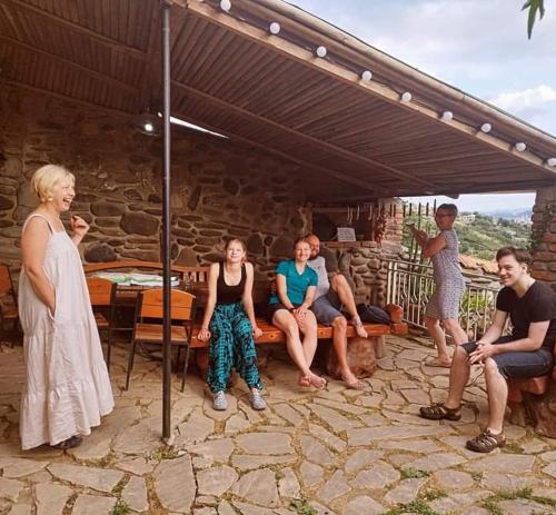 eine Gruppe von Menschen, die auf einer Bank unter einer Terrasse sitzen in der Unterkunft safari house in Tbilisi City