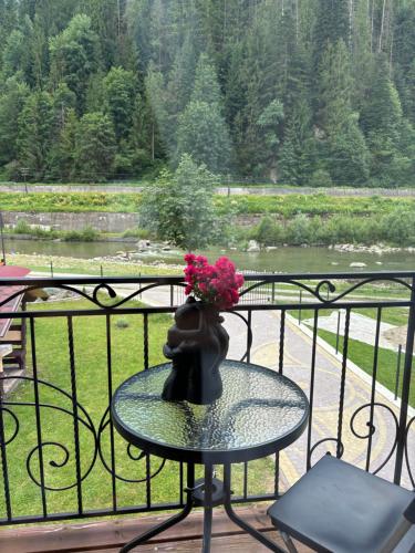 un jarrón con flores sentado en una mesa en un balcón en River House, en Yaremche