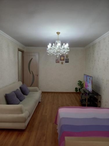 a living room with a couch and a chandelier at Elos-Home in Tbilisi City