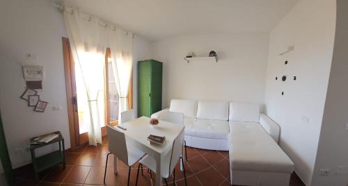 een woonkamer met een witte bank en een tafel bij Casa Vacanza Portu Maga (Marina di Arbus-Sardegna) in Portu Maga