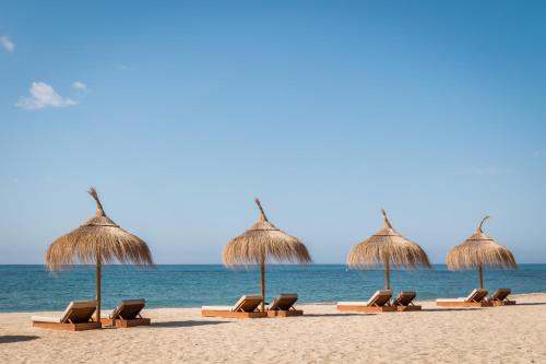 - une rangée de parasols et de chaises en paille sur la plage dans l'établissement Estival Centurión Playa, à Cambrils