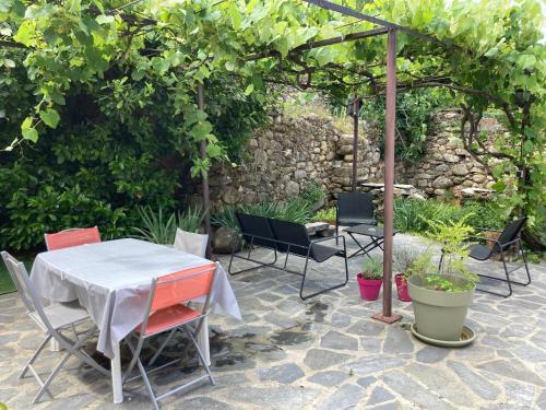 een patio met een tafel en stoelen en een parasol bij Maison Kyprea: charmant appartement /duplex , spacieux, tout confort avec terrasse extérieure privée, parking privatif , vue pittoresque sur la citadelle de Corté et les montagnes. in Corte