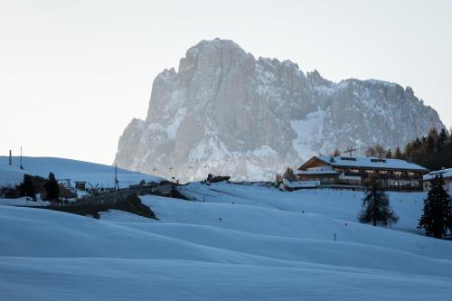 una montaña cubierta de nieve frente a un edificio en Berghotel Zorzi, en Alpe di Siusi