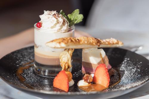 a dessert on a black plate with ice cream and fruit at Hotel Bergwelt in Längenfeld